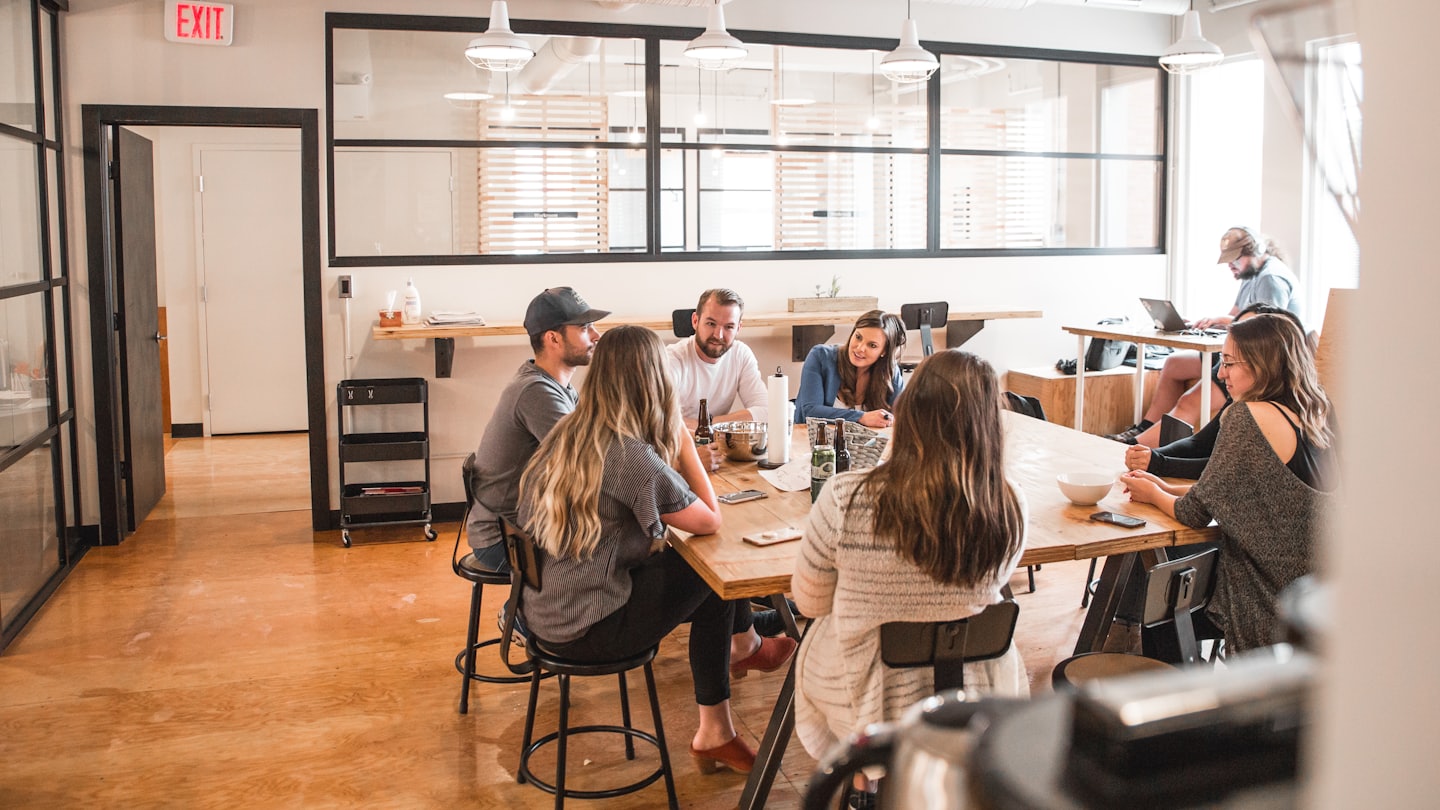 Diverse professionals die samenwerken aan een houten tafel in een modern kantoor.