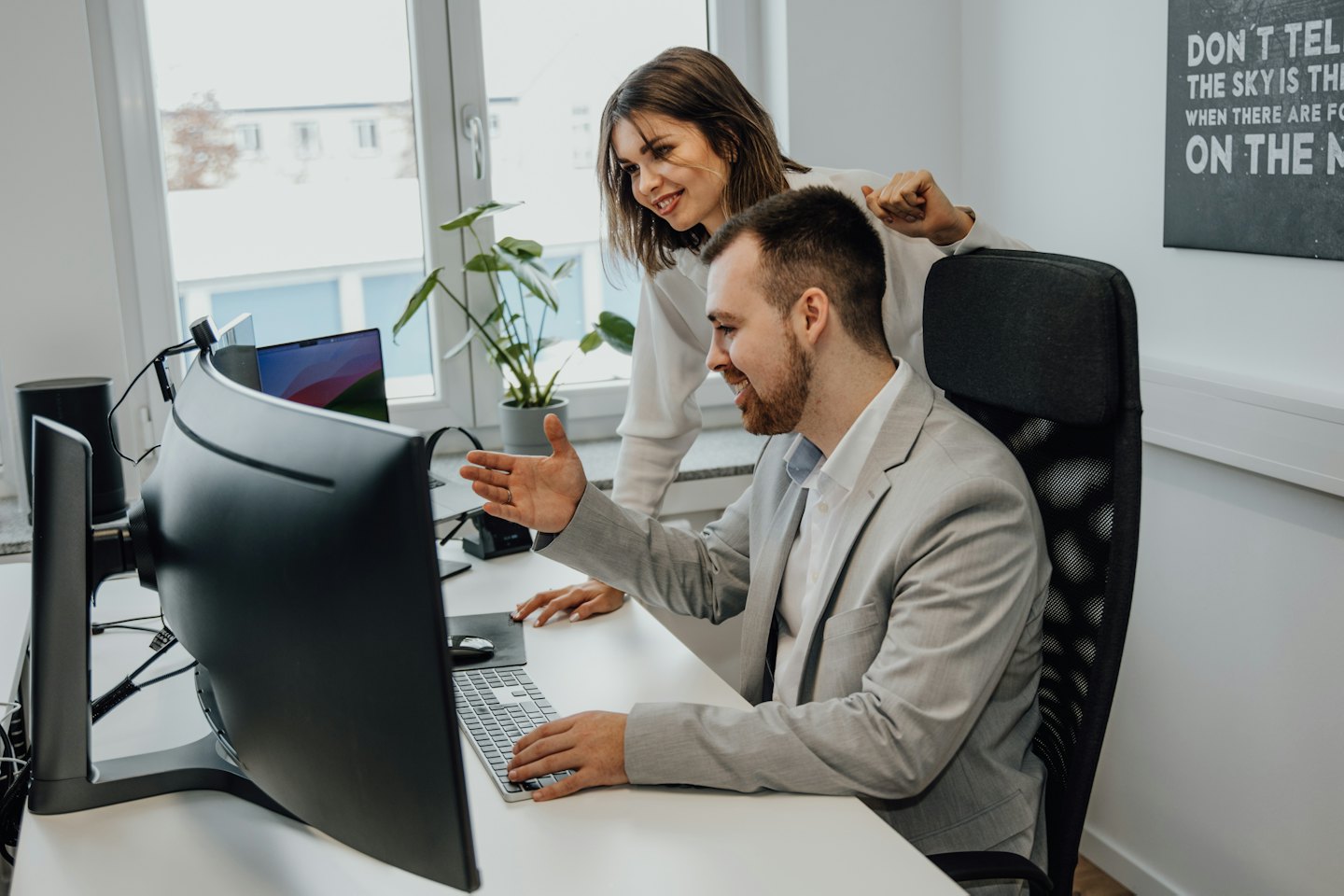 Twee collega's werken samen aan een bureau in een modern kantoor.