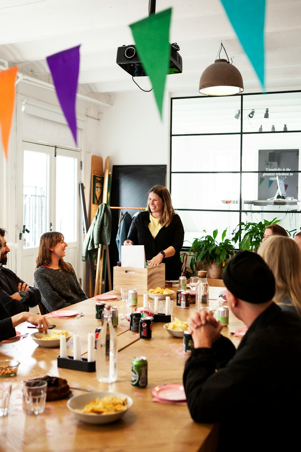 Diverse professionals die rond een tafel met eten en drinken vergaderen.