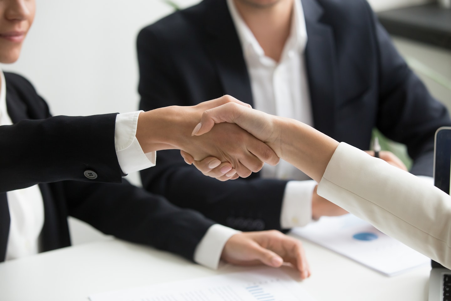 Twee zakelijke professionals geven elkaar de hand aan een bureau op kantoor.