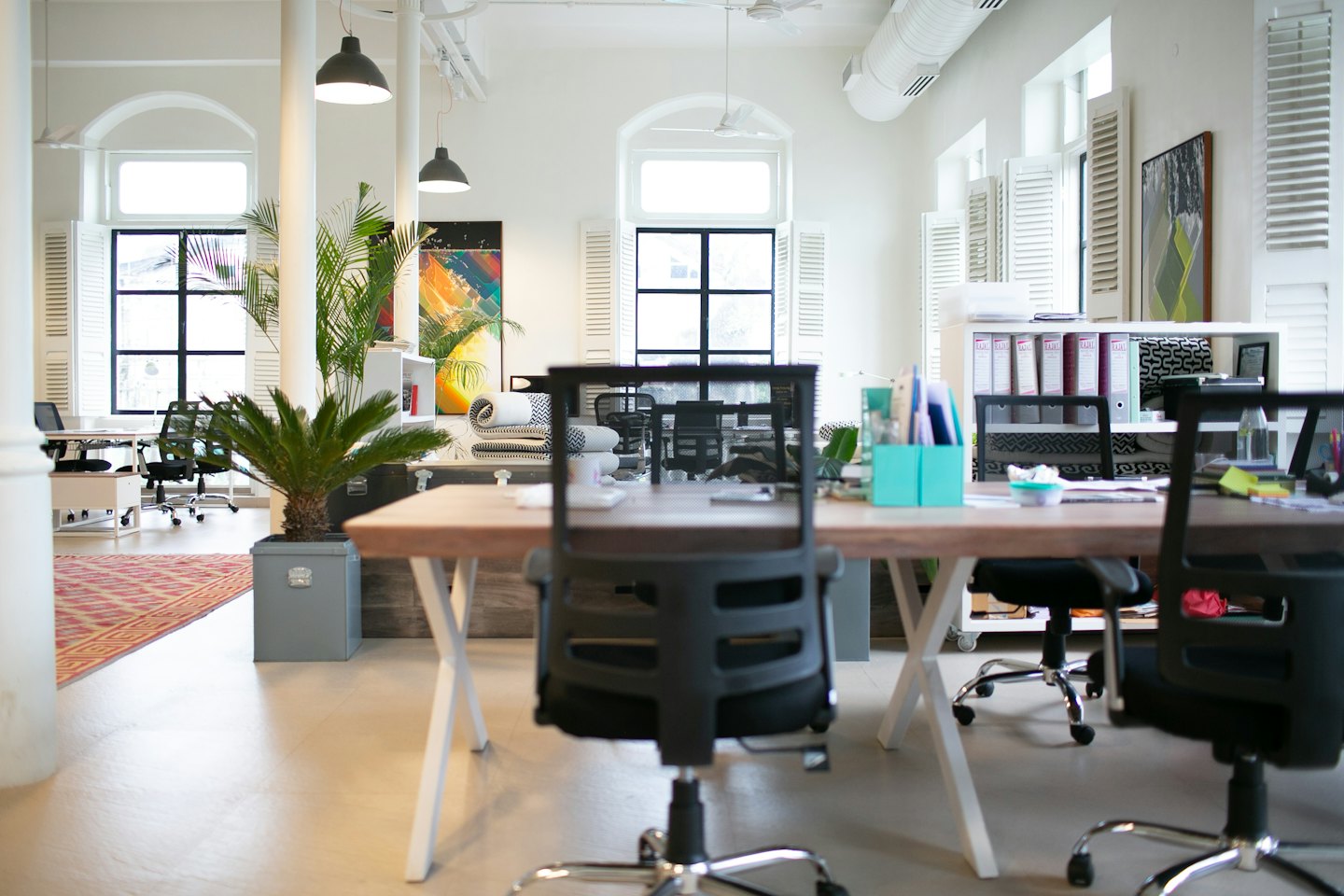 Moderne open kantoorruimte met lichte houten bureaus en grote ramen.