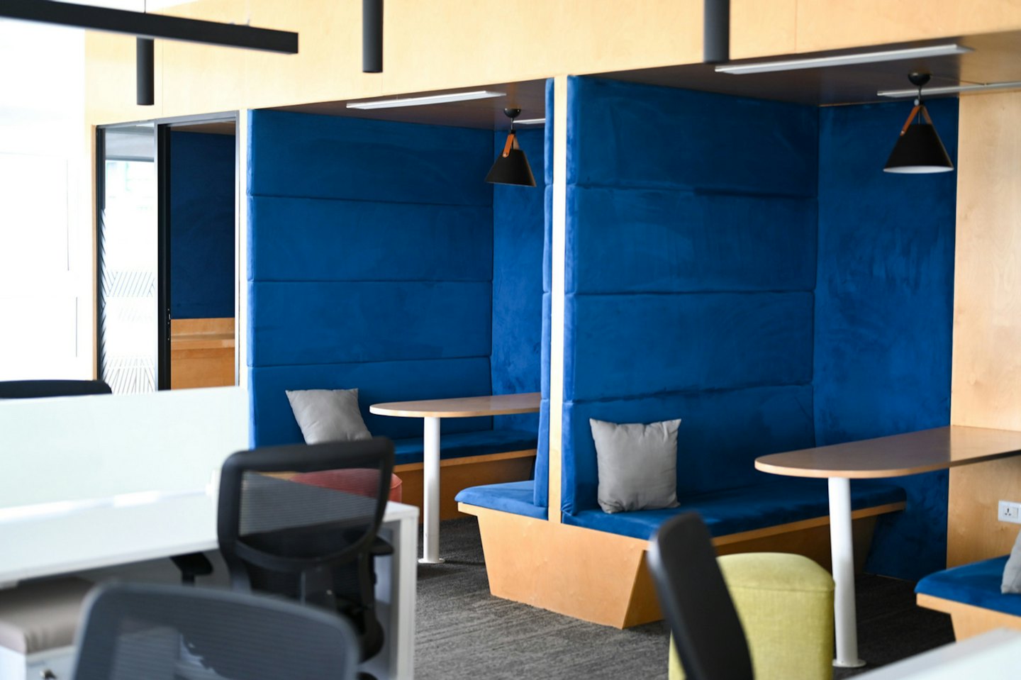 Moderne kantoorunits met blauwe zitplaatsen en lichte houten lambrisering.