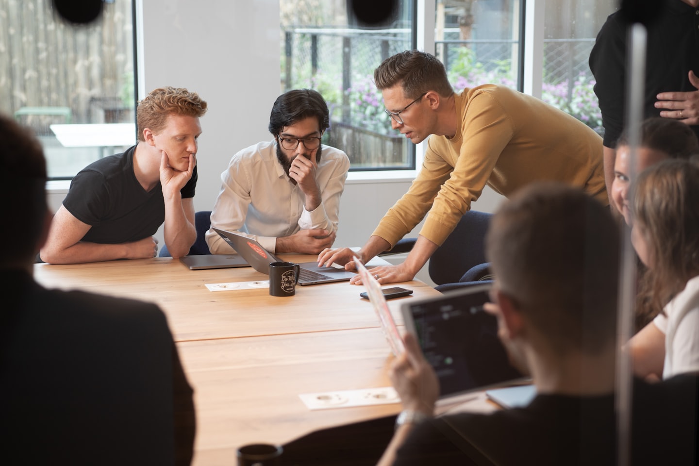 Professionals die samenwerken rond een conferentietafel met laptops.